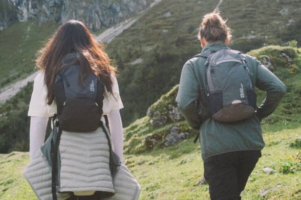 Sommerliche Aufnahme von zwei Wanderern mit Wanderrucksäcken im sportlichen Look von hinten