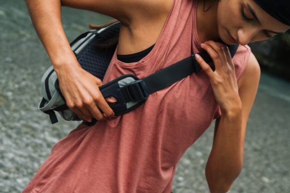 Junge Frau in sportlicher, sommerlicher Wanderkleidung mit sportlicher Umhängetasche